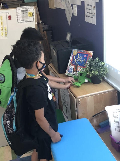 Two students hanging out with a Zac stuffed animal at school.